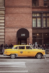 Clean, black and yellow taxi waiting in front of a modern office building.