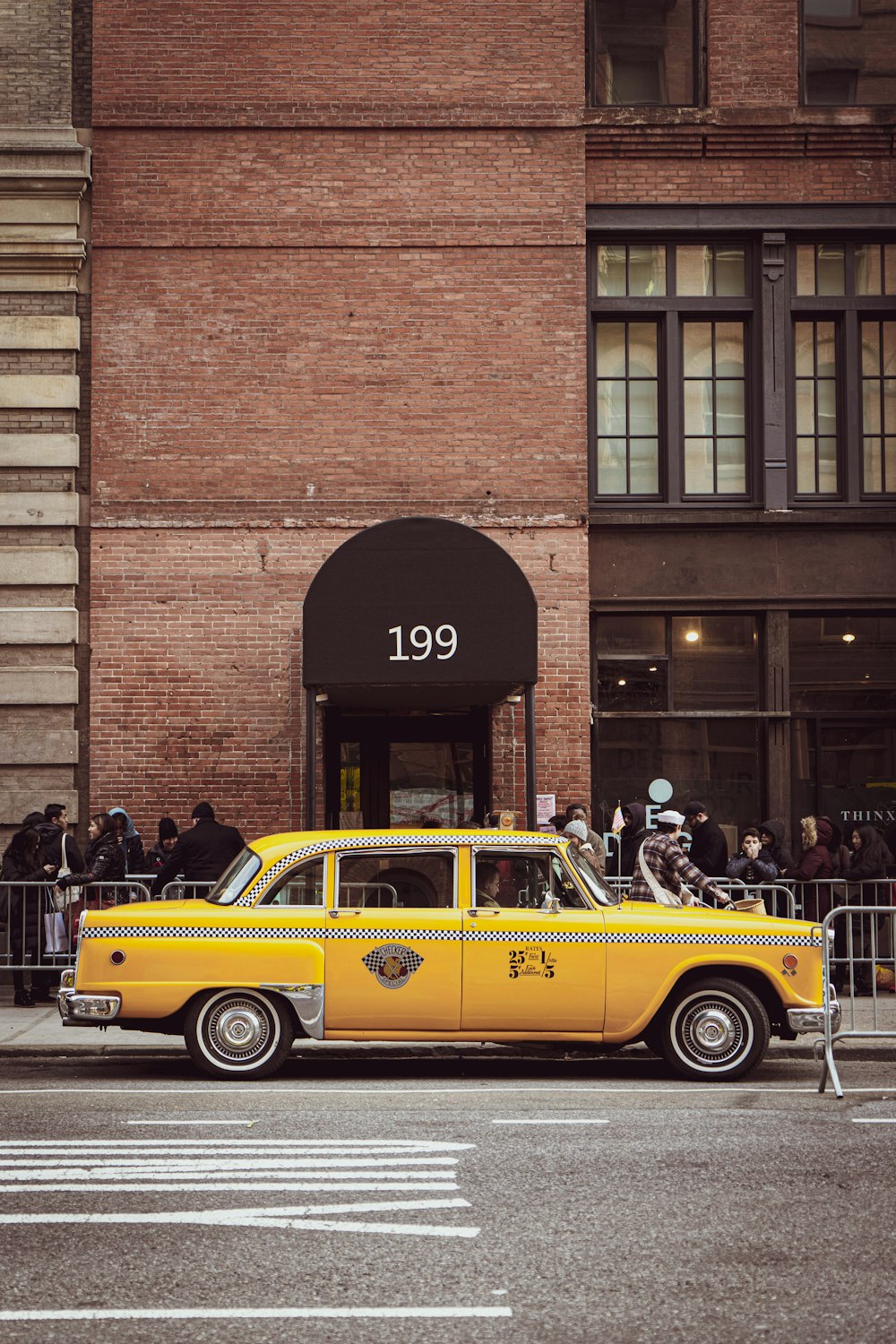 Taxi amarillo aparcado junto a un edificio de ladrillos marrones