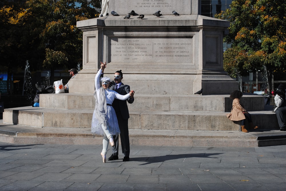 man and woman standing in front of white concrete building during daytime