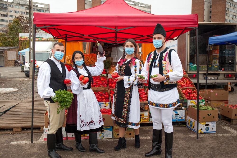 3 women and 2 men standing near red canopy tent