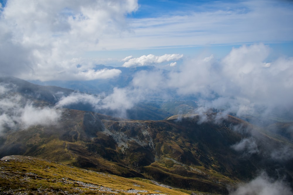 green and brown mountain under white clouds and blue sky during daytime