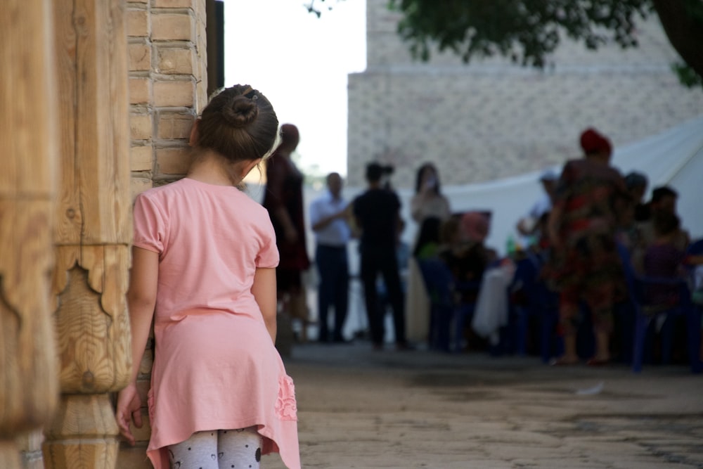 woman in pink dress standing on street during daytime