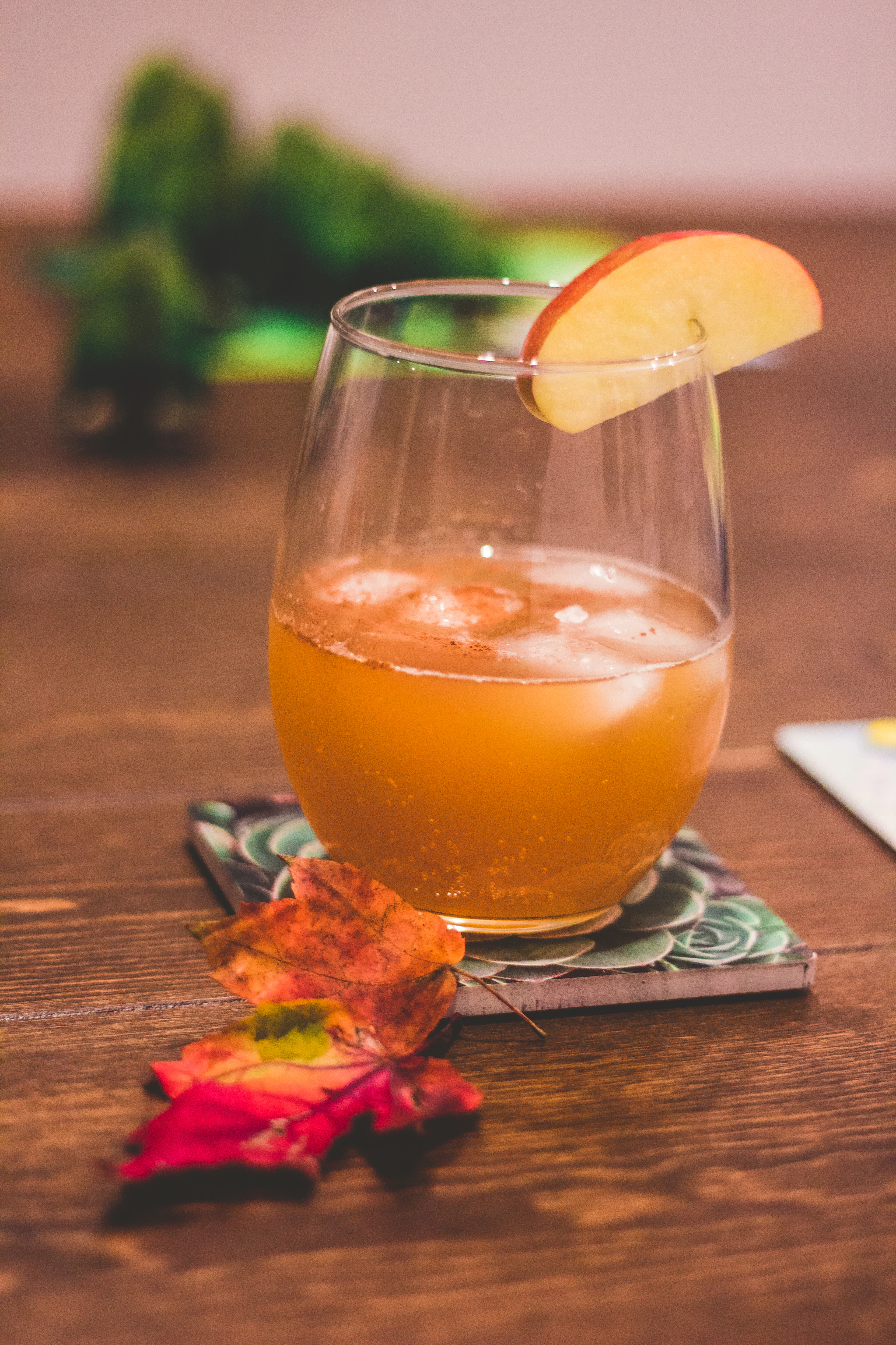 A glass of cloudy apple wine on a coaster, condensation running down the side