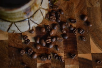 A variety of coffee beans and brewing tools arranged artistically on a rustic wooden surface.
