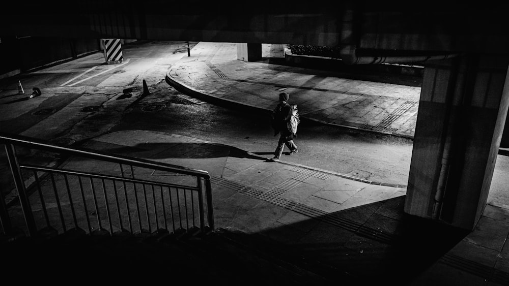 grayscale photo of person walking on sidewalk