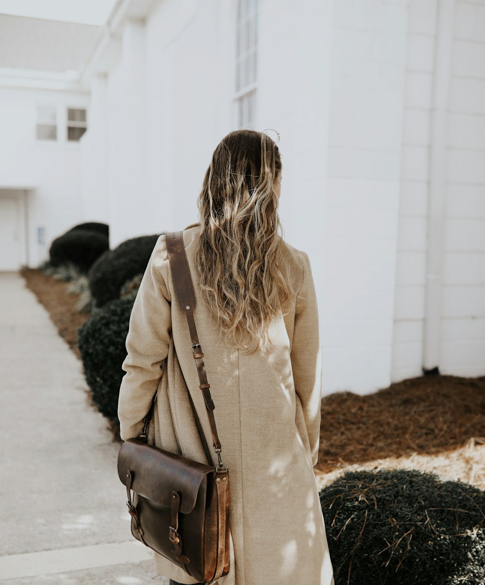 woman in beige long sleeve shirt and brown leather shoulder bag