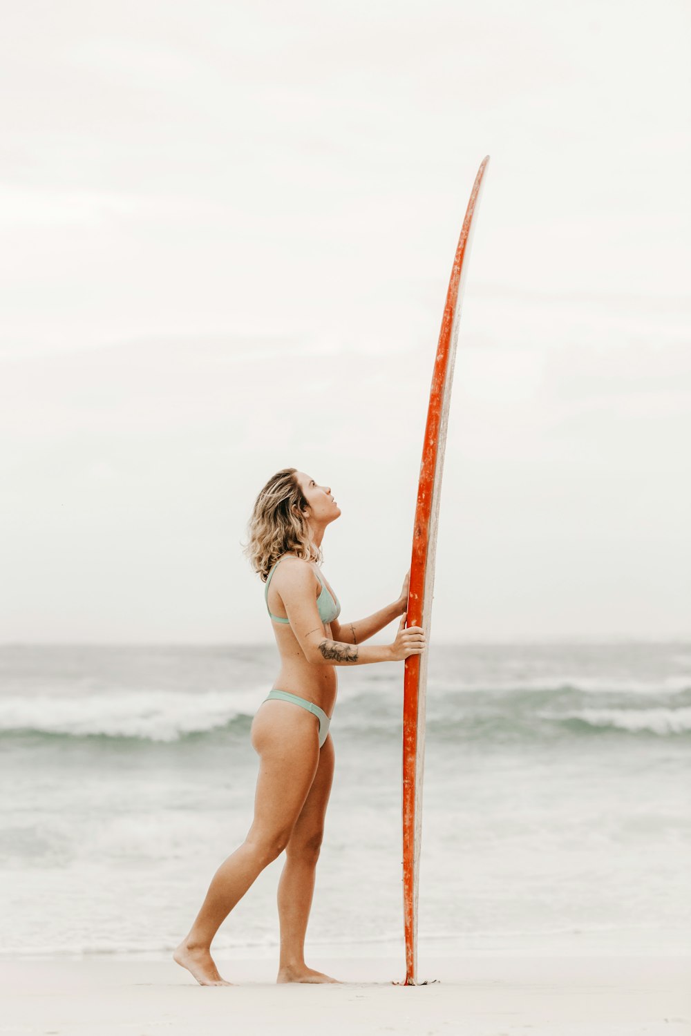 woman in pink bikini holding on brown wooden pole