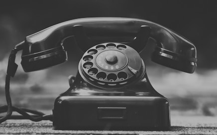 black rotary phone on gray textile