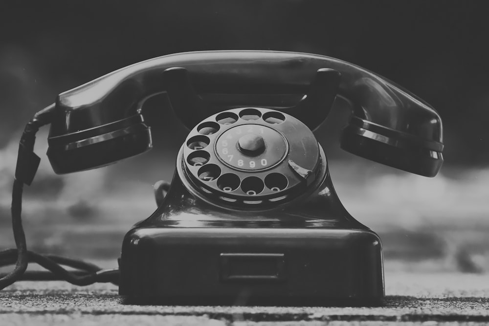 black rotary phone on gray textile