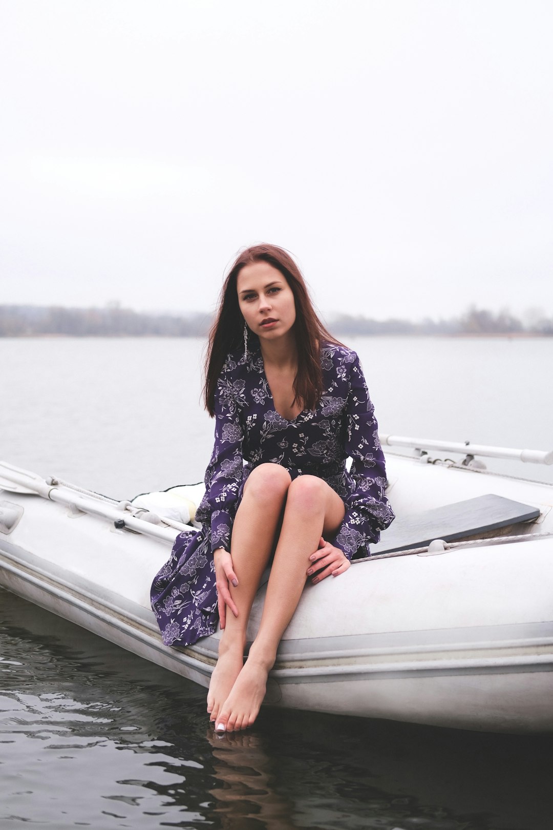woman in black and white floral dress sitting on white boat during daytime