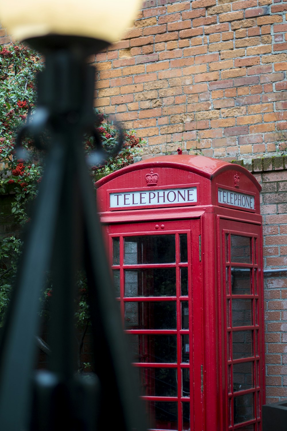 red telephone booth beside brown brick wall