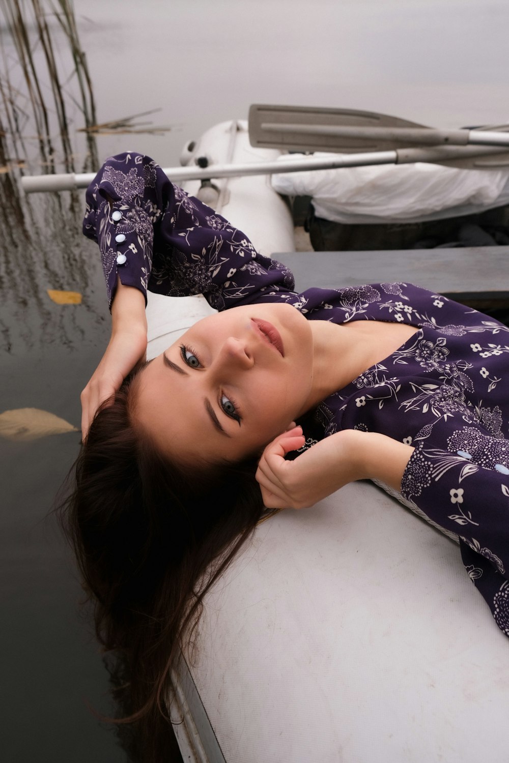 woman in purple and white floral long sleeve shirt lying on bed