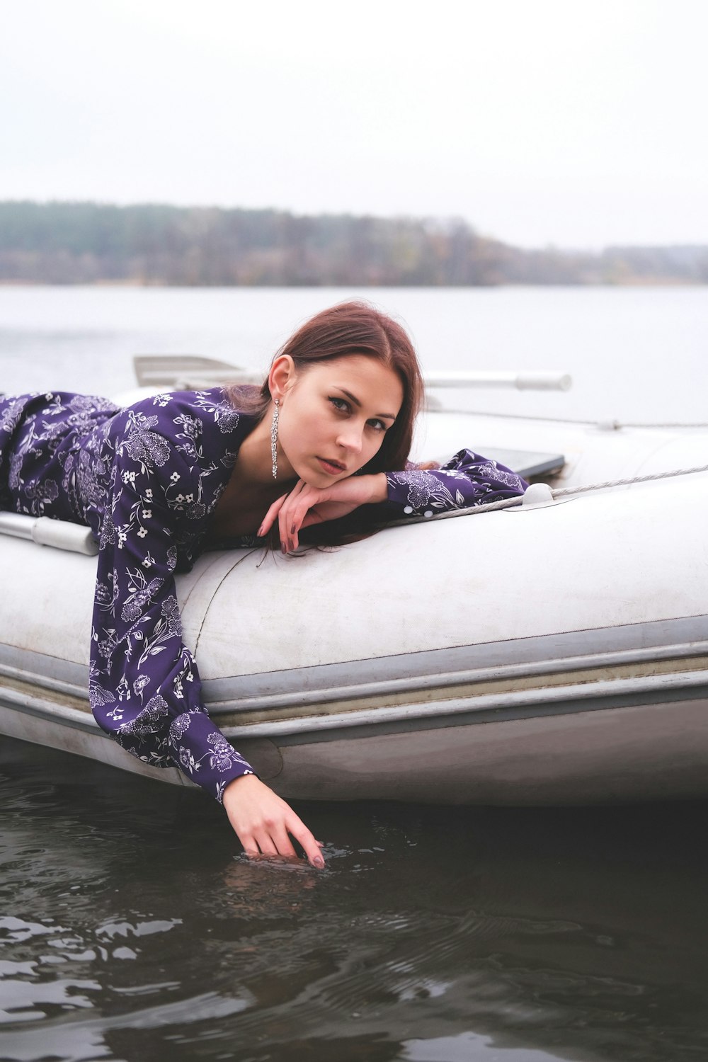 Mujer en vestido floral blanco y negro que yace en un barco blanco durante el día