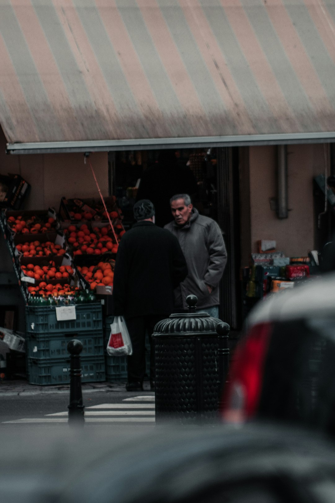 man in black jacket standing near fruit stand during daytime
