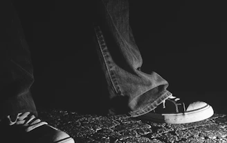 A dynamic photo of sleek, distressed denim jeans styled with chunky sneakers on a city sidewalk.