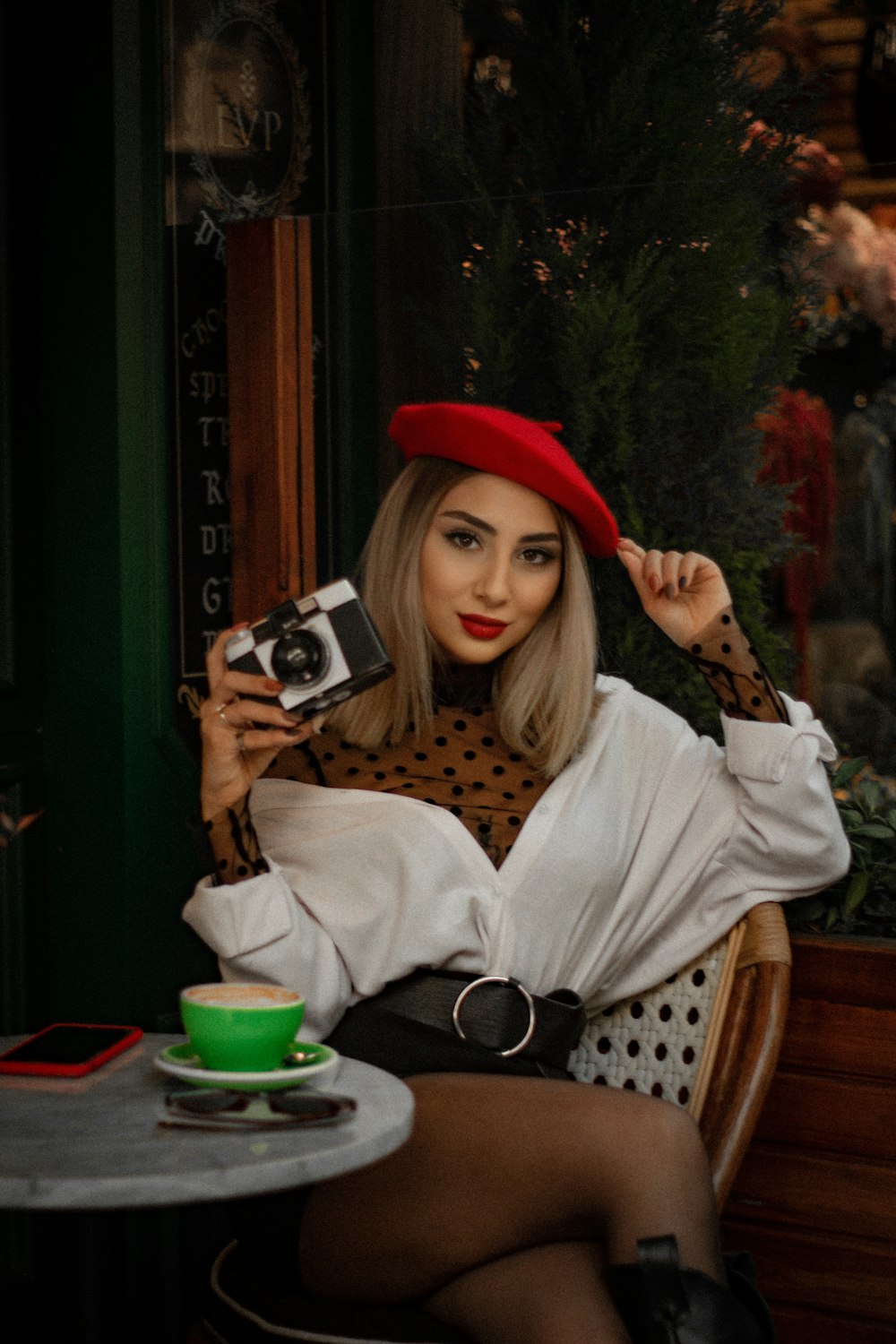 woman in white sweater holding silver and black camera