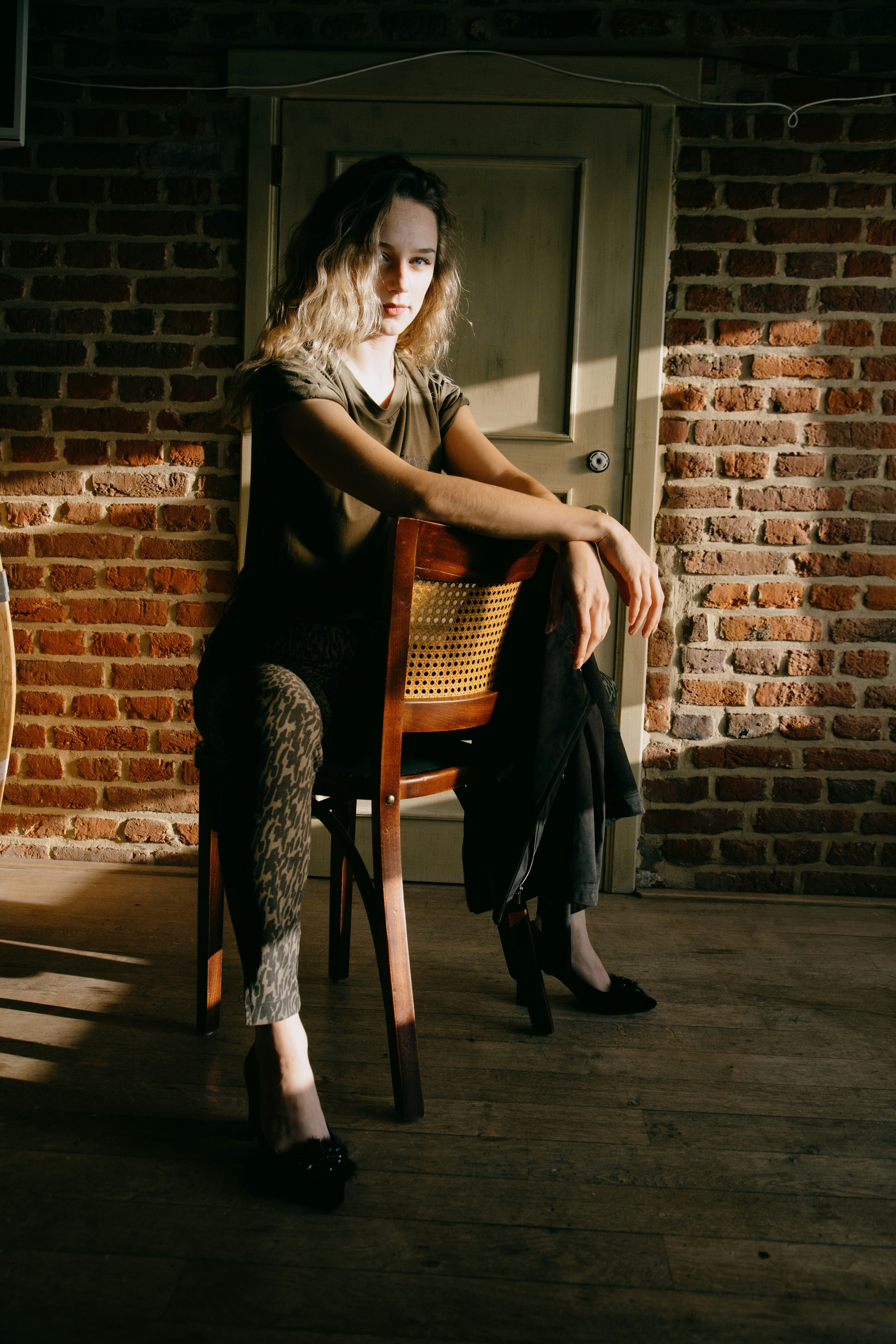 woman in black dress sitting on brown wooden chair