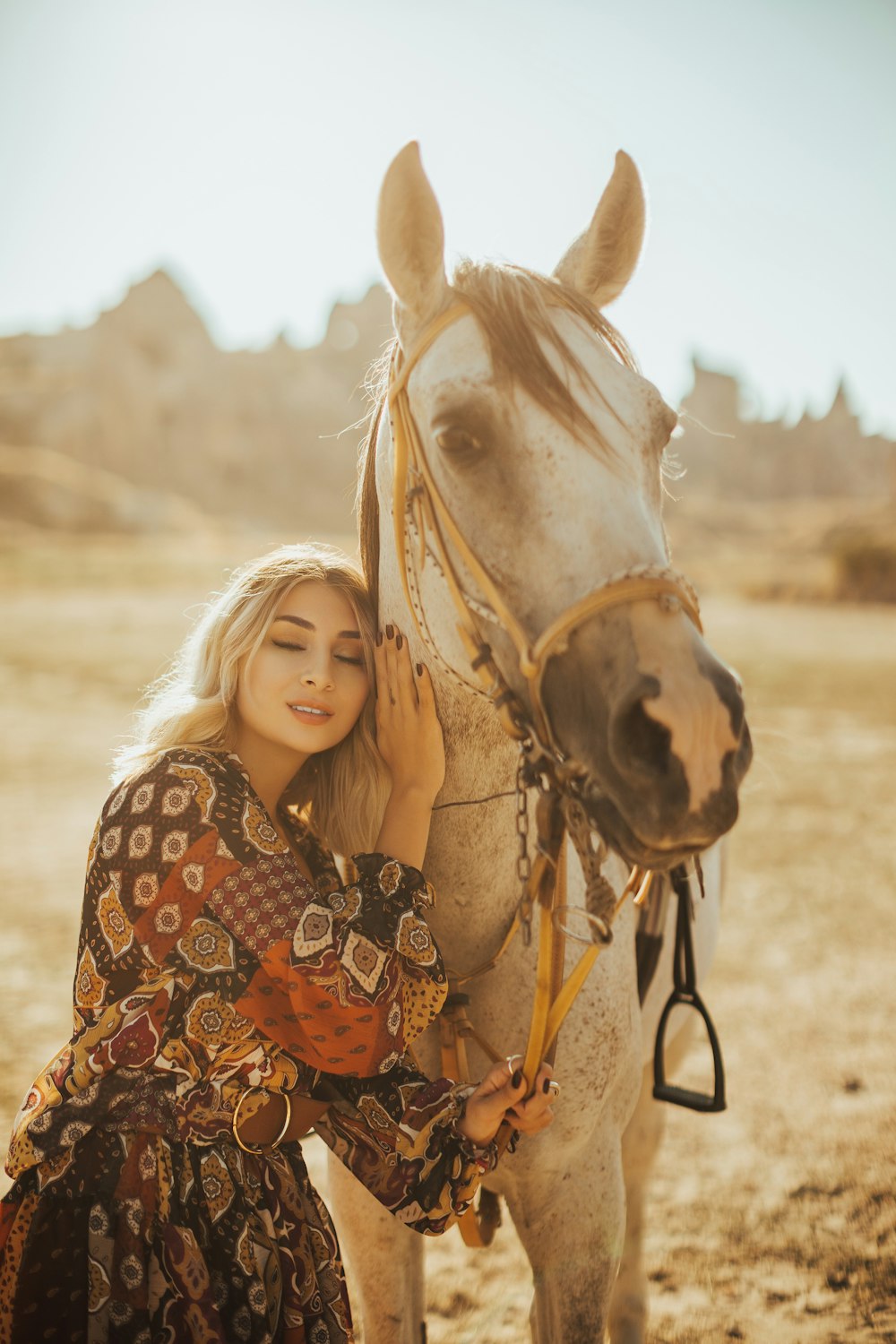 donna in camicia a maniche lunghe a pois in bianco e nero in piedi accanto al cavallo marrone durante il giorno