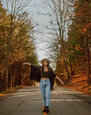 Person wearing a cozy wool hat walking along a leafy street in crisp autumn light.