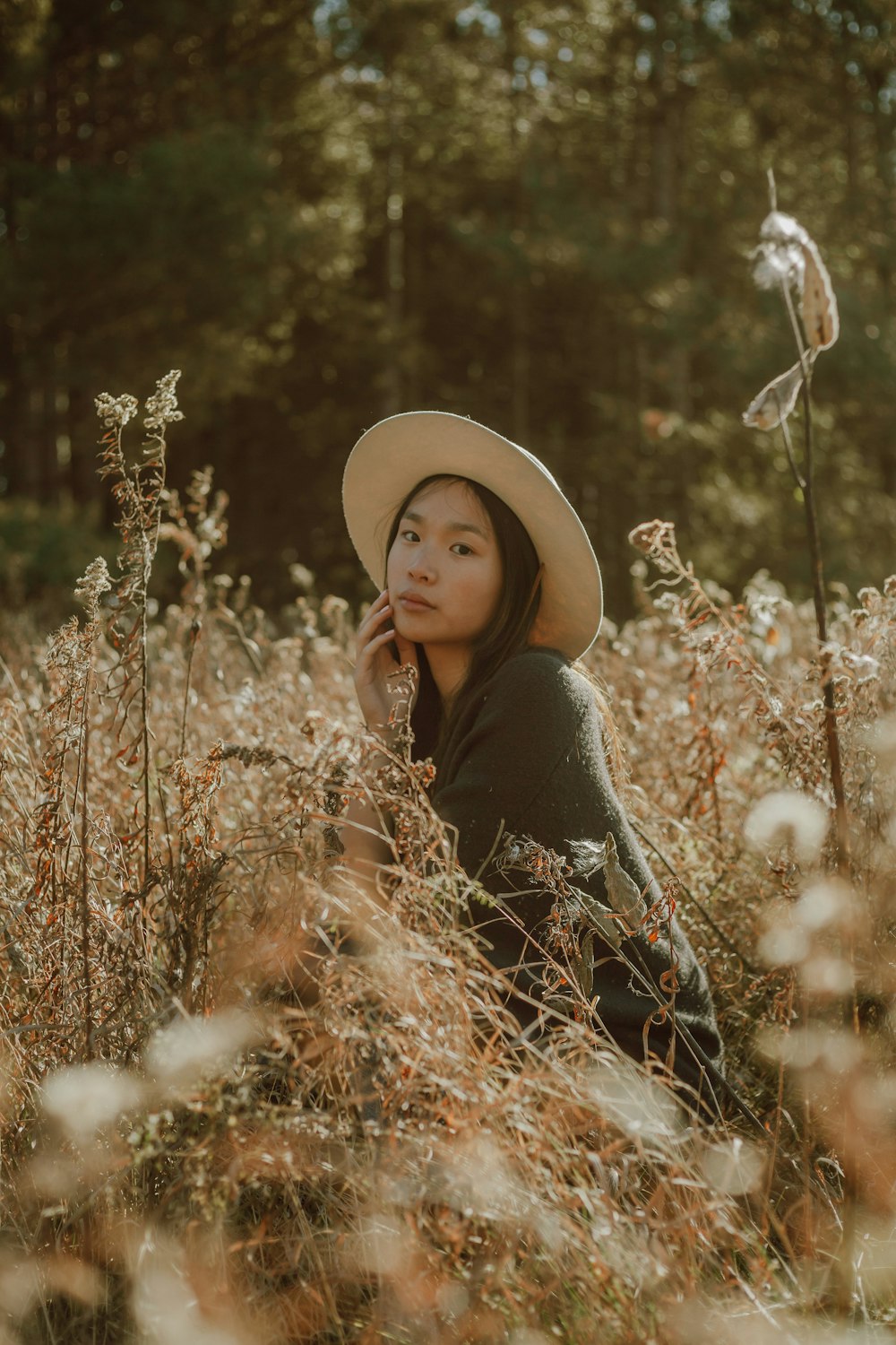 woman in black long sleeve shirt wearing beige sun hat standing on brown grass field during