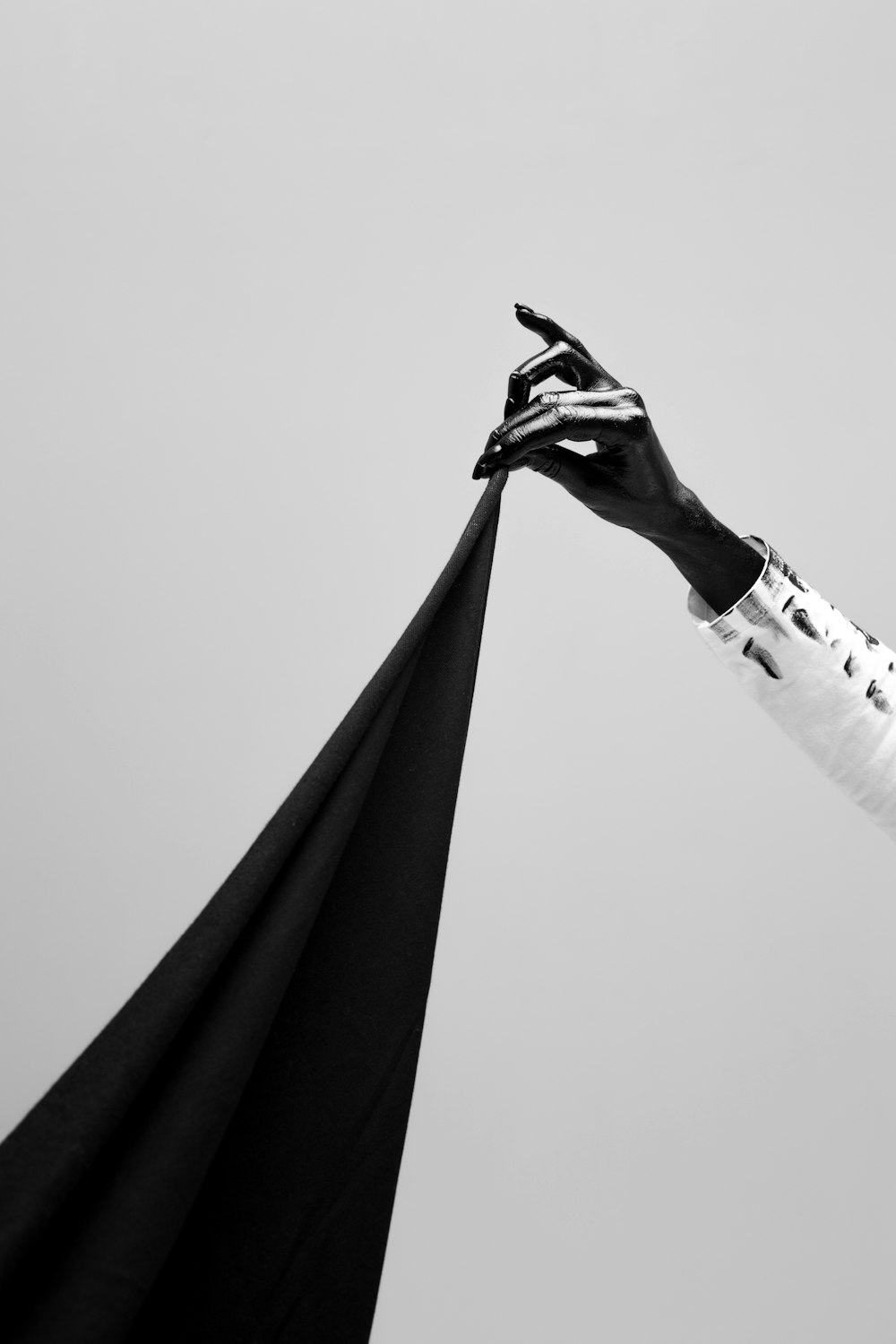 grayscale photo of man in black robe holding black umbrella