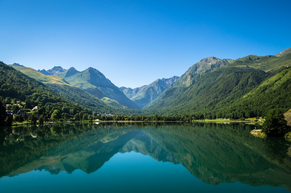 Montañas verdes junto al lago bajo el cielo azul durante el día