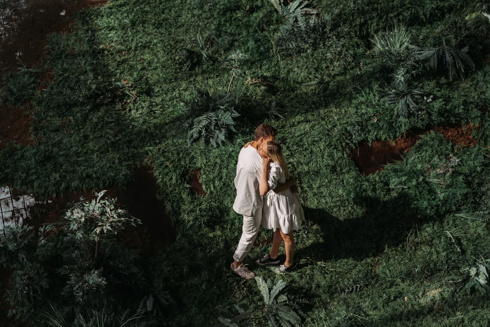 woman in white long sleeve shirt and gray pants standing beside green plants during daytime