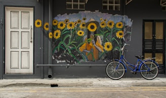 blue bicycle parked beside blue and yellow floral wall