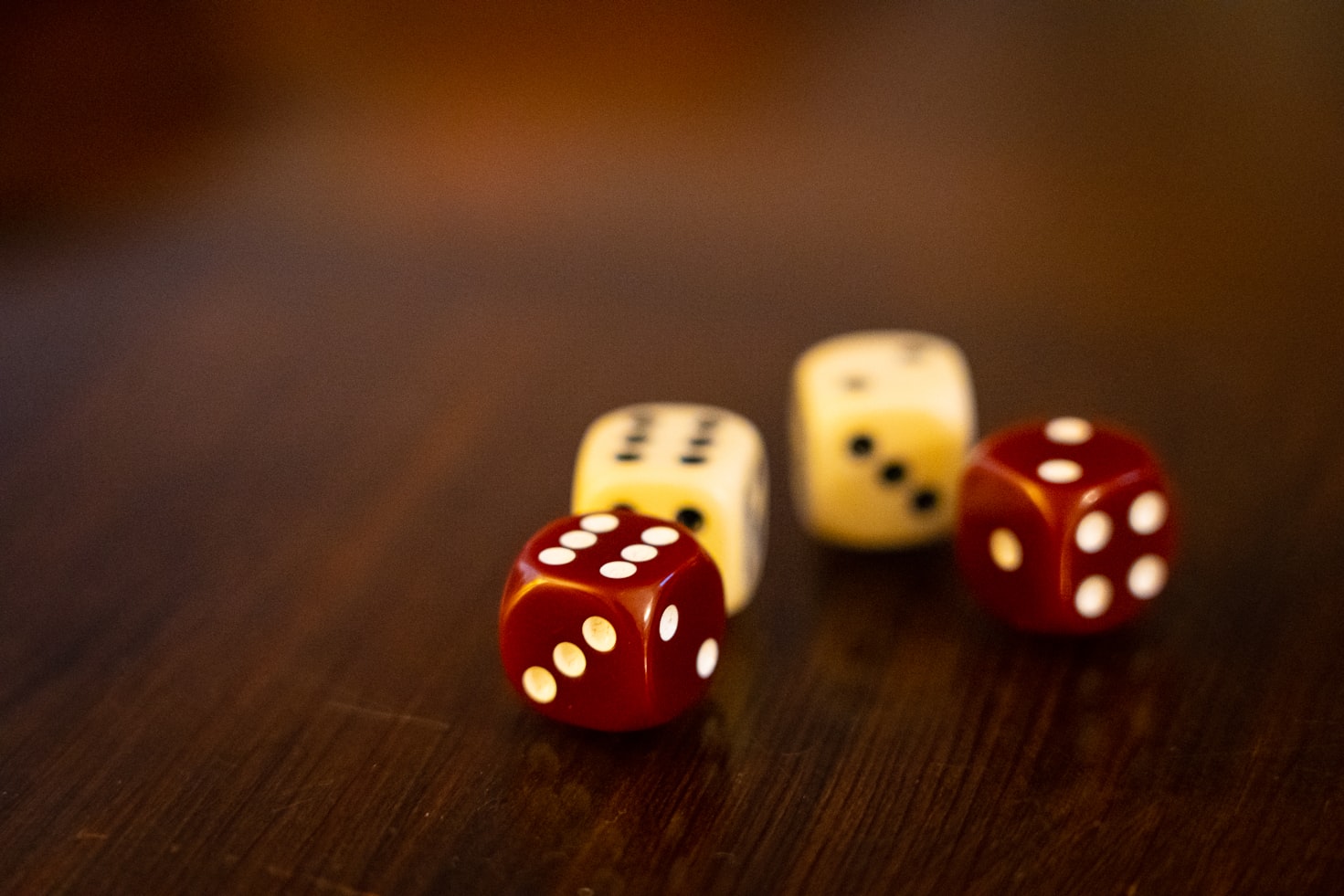 Two red dice and two white dice on a wooden table