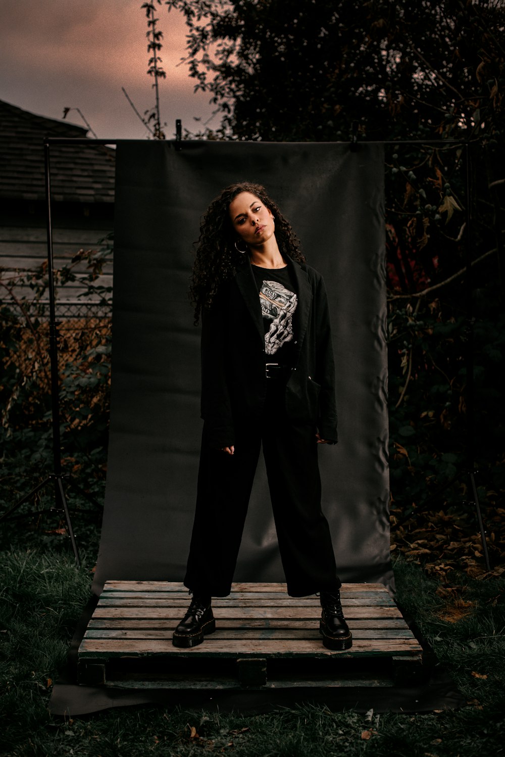 woman in black coat standing near black curtain