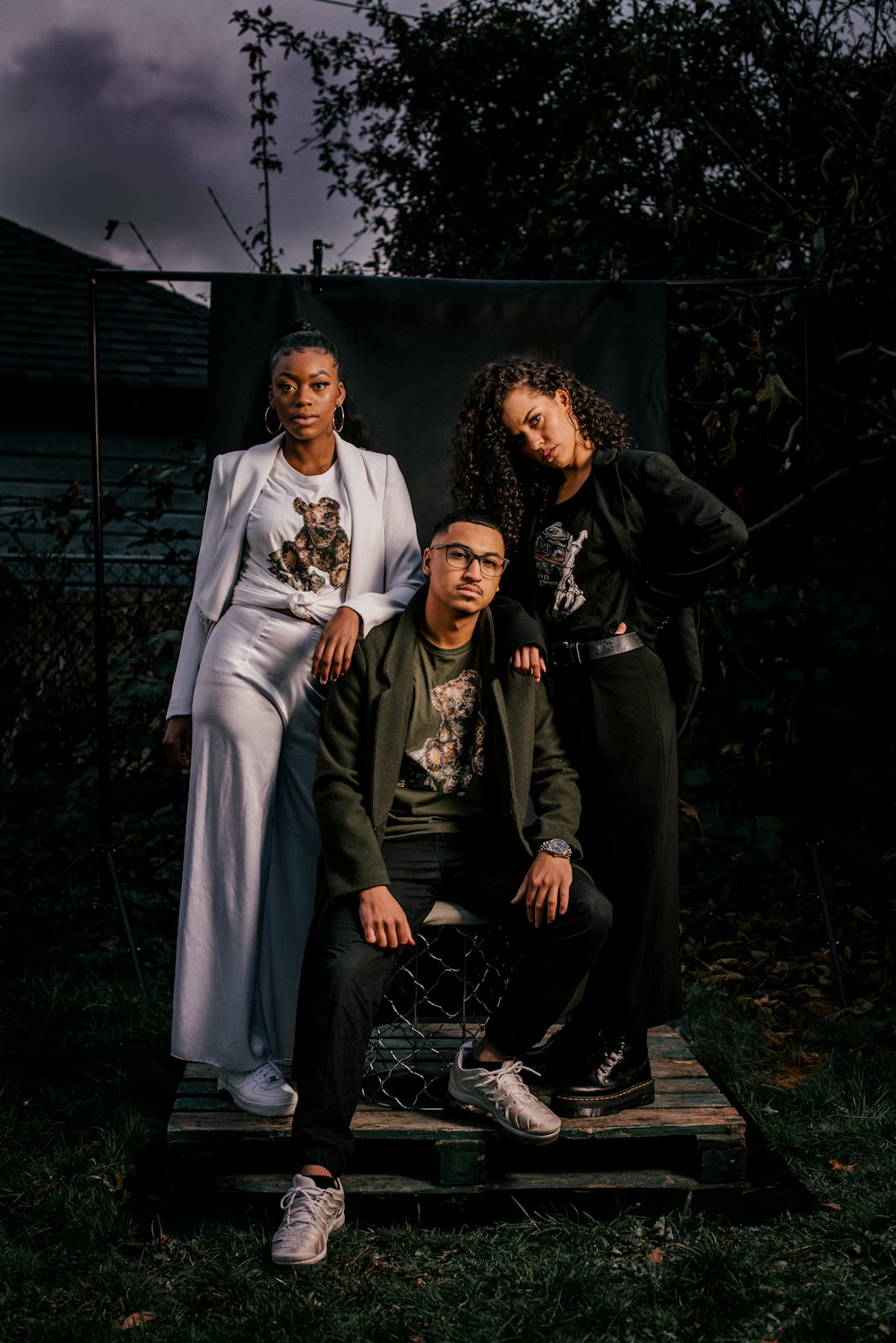 3 women sitting on black metal fence during night time