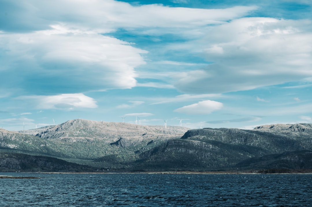 mountain ranges near body of water under cloudy sky during daytime