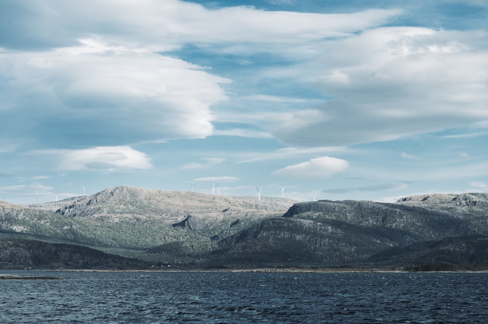 mountain ranges near body of water under cloudy sky during daytime