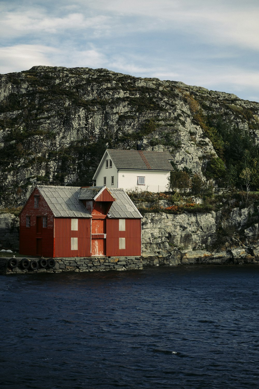 casa di legno rossa e bianca accanto allo specchio d'acqua durante il giorno
