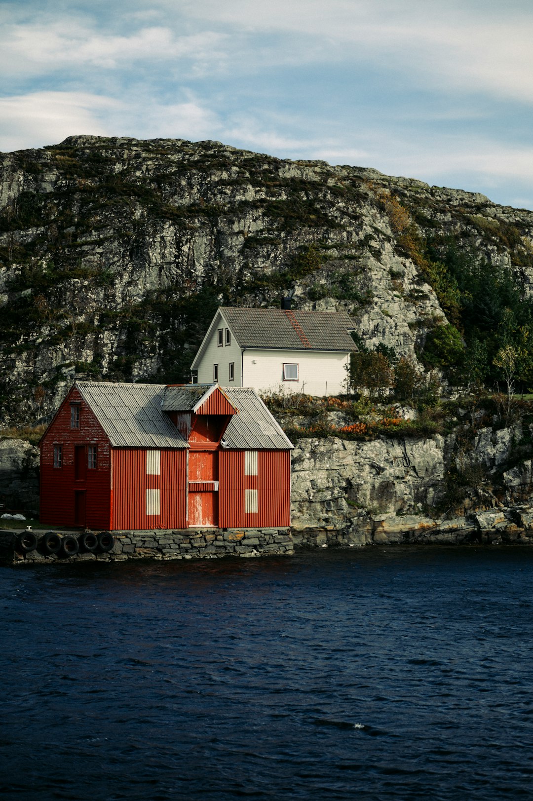 red and white wooden house beside body of water during daytime