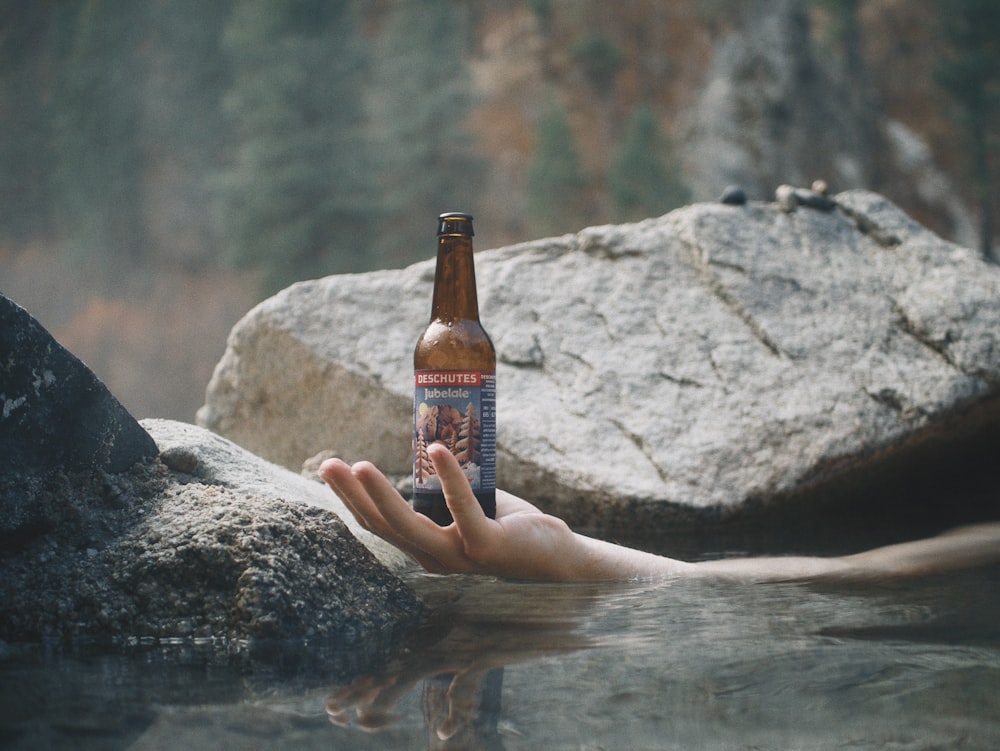 brown glass bottle on gray rock