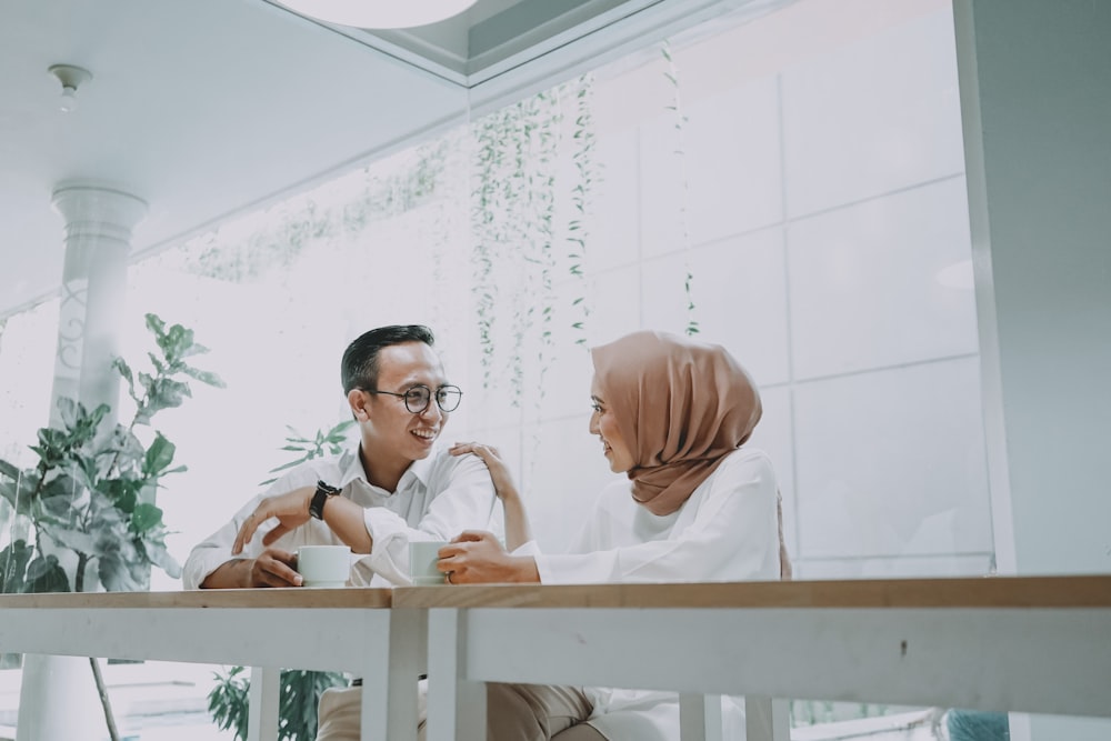 man in white dress shirt sitting on brown wooden chair