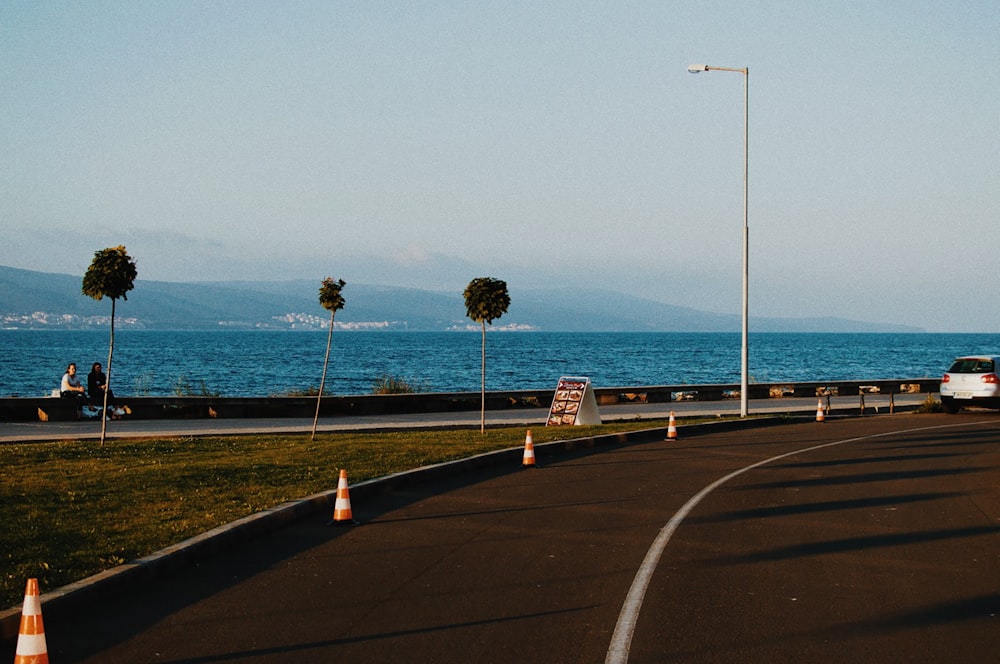 gray concrete road near body of water during daytime