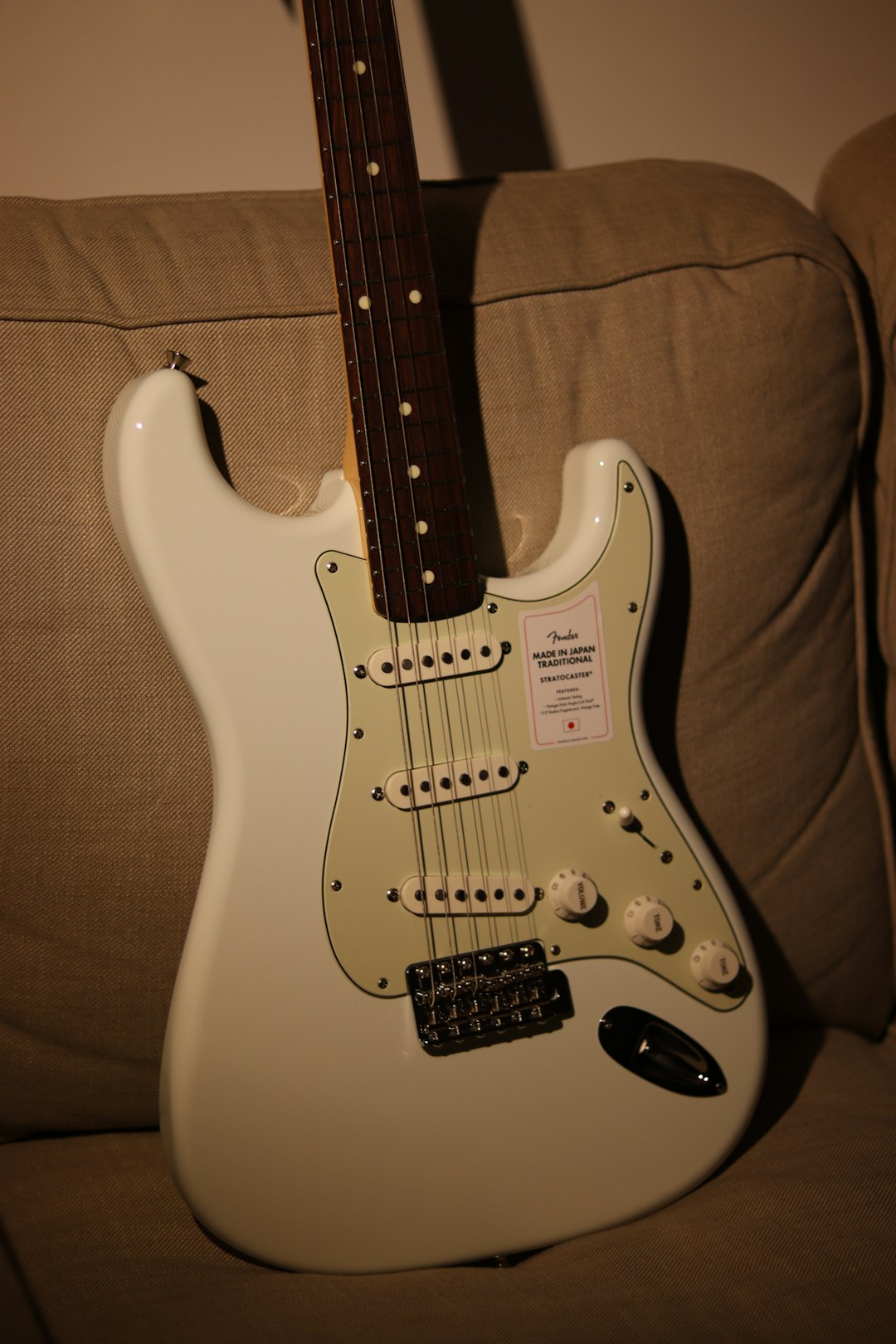 white and brown stratocaster electric guitar