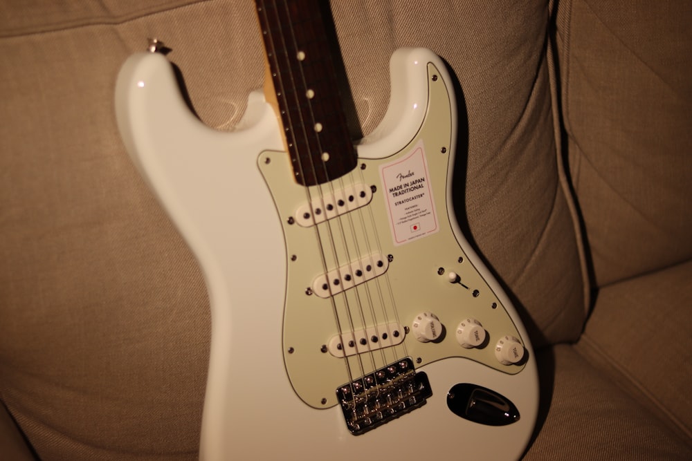 white and brown stratocaster electric guitar