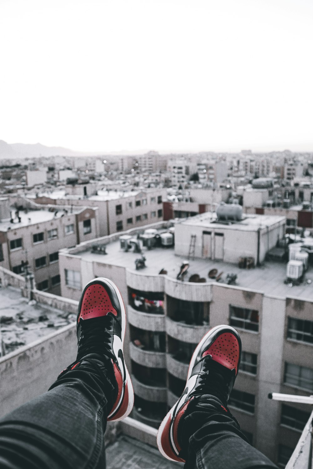 person in black and red sneakers sitting on top of building