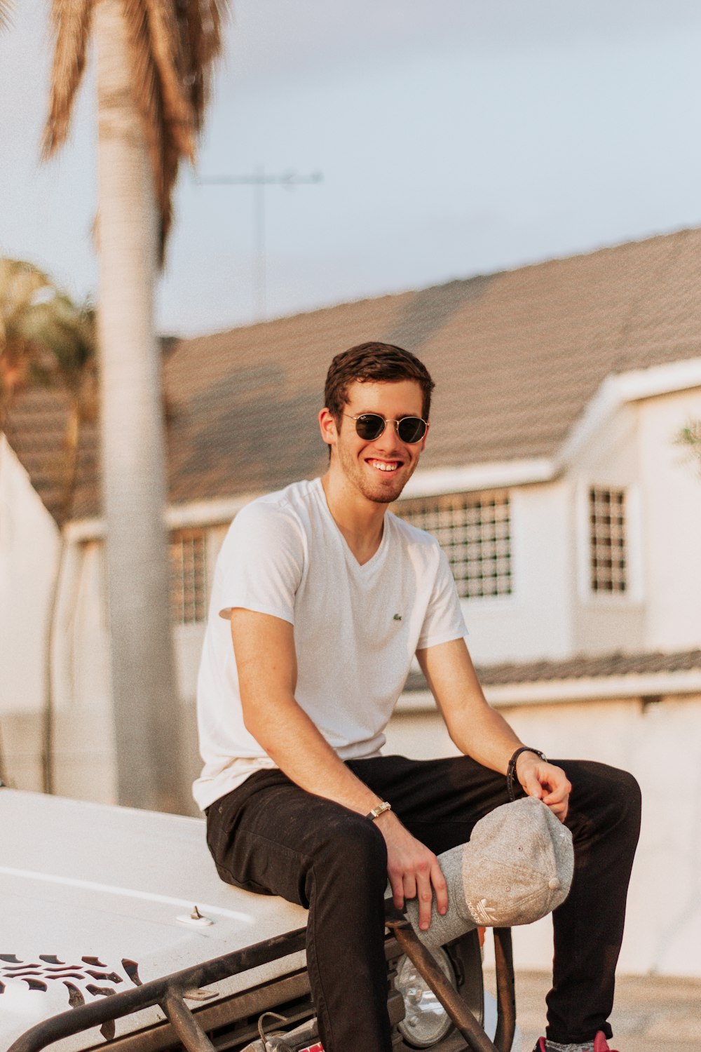 man in gray crew neck t-shirt and blue denim jeans sitting on white concrete wall