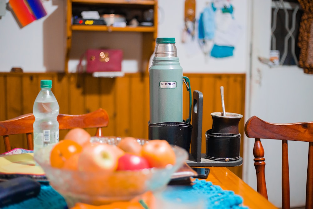 stainless steel vacuum flask beside orange fruits on blue tray