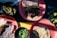 A variety of Mexican dishes with grilled meat and tortillas are placed on pink plates. A selection of sides including green chili peppers, lime wedges, and green salsa are served in small black bowls.
