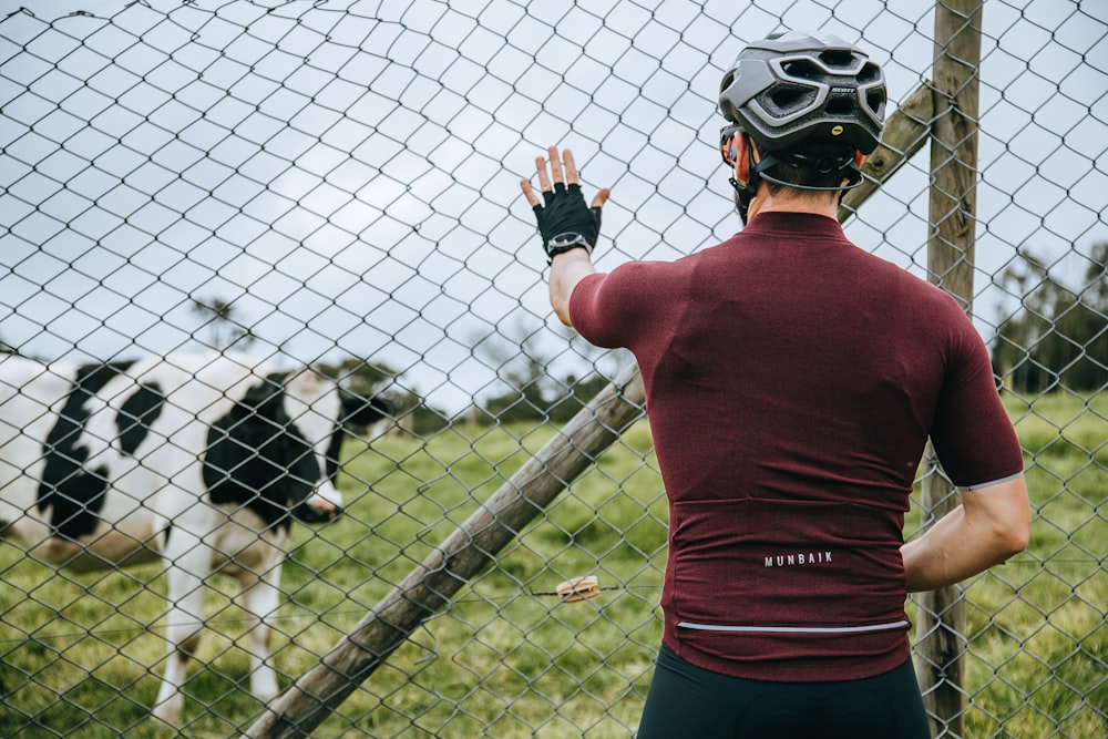 man in red long sleeve shirt standing beside white and black dog