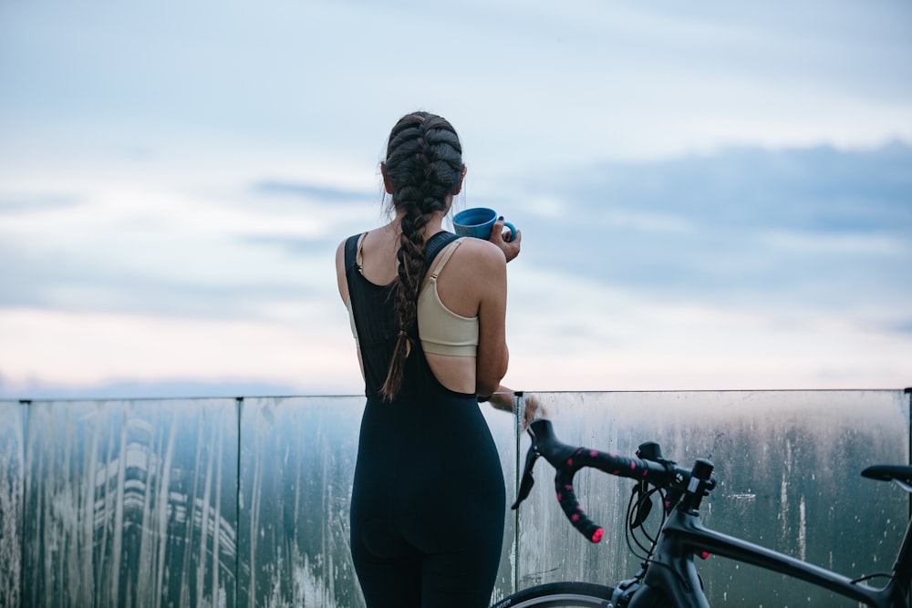 femme en débardeur noir et leggings noirs tenant un vélo noir