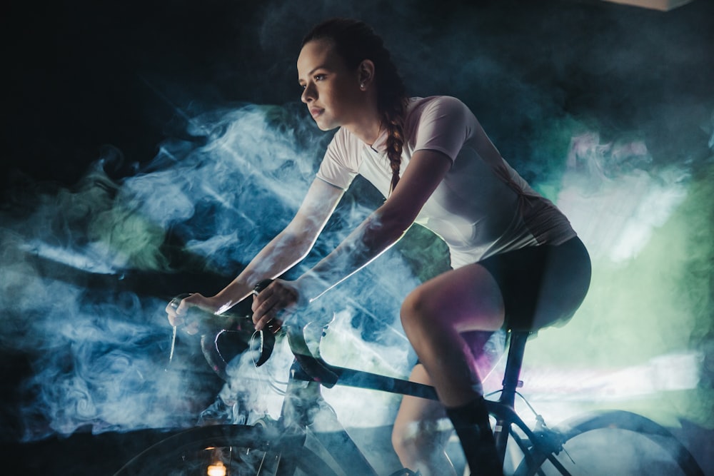 woman in white shirt and black shorts sitting on black metal bar