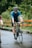 man in blue crew neck t-shirt riding black bicycle on road during daytime