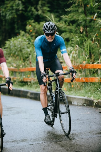 man in blue crew neck t-shirt riding black bicycle on road during daytime