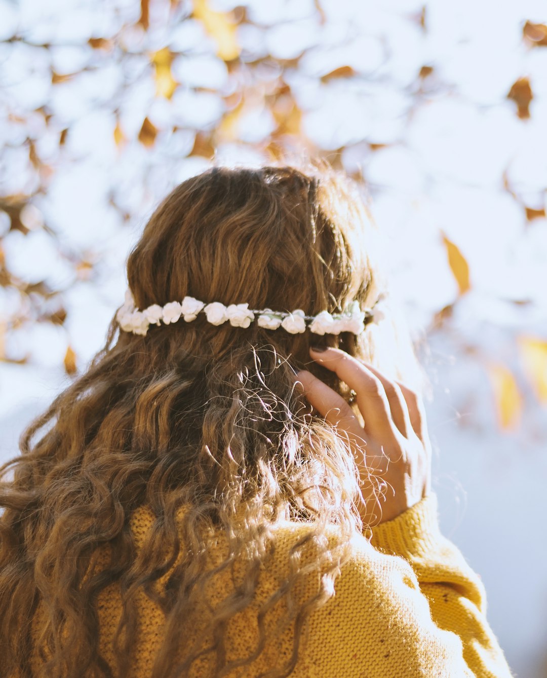 woman in brown knit sweater covering her face with her hands